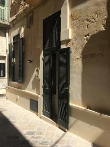 a building with green shutters on it at Lo Scrigno Barocco in Lecce