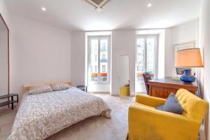 um quarto com uma cama e um sofá amarelo em Lovely large familial apartment in central Nice, ten minutes walk to the beach! em Nice