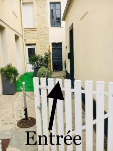 une flèche apposée sur une clôture blanche devant une maison dans l'établissement La Crabette Bleue, à Grandcamp-Maisy