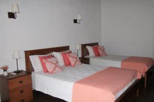 2 łóżka w sypialni z białymi i czerwonymi poduszkami w obiekcie Quinta da Figueirinha w mieście Marvão