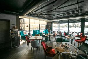 un restaurante con muchas mesas, sillas y ventanas en FLOW, en Belgrado