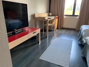 Una sala de estar con un televisor de pantalla plana y una mesa. en Hotelli Haapajärvi, en Haapajärvi