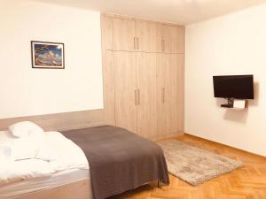 a bedroom with a bed with a cabinet and a television at Heroes’ Residence II in Budapest