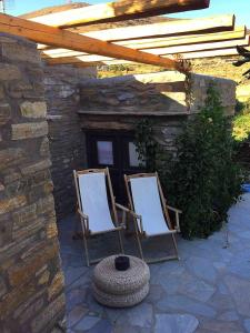 dwa krzesła siedzące na patio pod dachem w obiekcie Stone house by Anemos w mieście Agios Ioannis