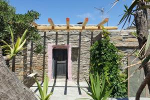 a stone building with a black door and some plants at Stone house by Anemos in Agios Ioannis