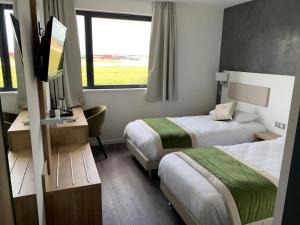 a hotel room with two beds and a television at ATOLON PARK HOTEL in Brumath