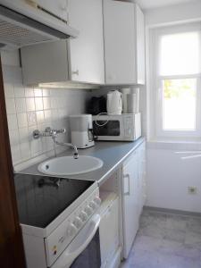 een witte keuken met een wastafel en een magnetron bij Haus Charenza 1 in Garz