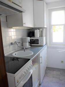 a white kitchen with a sink and a microwave at Haus Charenza in Garz-Rügen