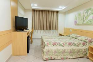 a hotel room with a bed and a flat screen tv at Hotel Domani in Guarulhos