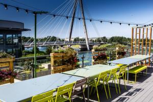 a deck with tables and chairs with a bridge in the background at Waterfront Southport Hotel in Southport