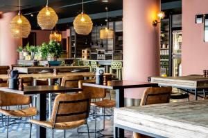 a restaurant with tables and chairs and pendant lights at Waterfront Southport Hotel in Southport