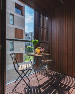 einen Tisch und Stühle auf einem Balkon mit einem großen Fenster in der Unterkunft 19 Dzielnica Kolejowa P&O Serviced Apartments in Warschau