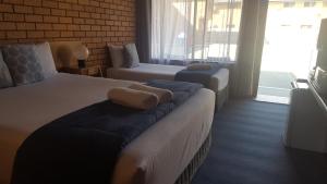 a hotel room with two beds and a couch at Royal Palms Motor Inn in Coffs Harbour