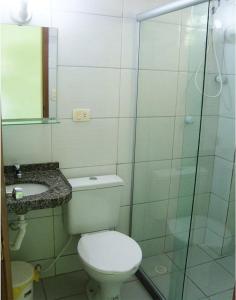 uma casa de banho com um WC e uma cabina de duche em vidro. em Pousada Ouriço em Porto de Galinhas