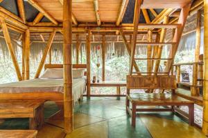 a bedroom with a bed and a bench in a room at Universo Pol Bamboo Hostel in Morro de São Paulo