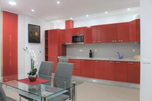 uma cozinha com armários vermelhos e uma mesa de vidro em Apart Baía do Sado II em Setúbal
