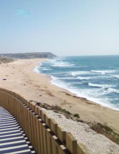 a beach with a fence next to the ocean at Azure Guest House in Silveira