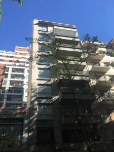a tall white building with a tree in front of it at Studio Palermo La Rural y Embajada USA in Buenos Aires