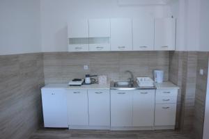 een kleine keuken met witte kasten en een wastafel bij HAMAM in Novi Pazar