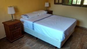Un dormitorio con una cama y una mesita de noche con una colcha blanca. en Casa de descanso "El Jagüel", en San Marcos Sierras