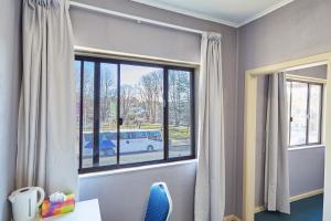 a room with a window with a table and a blue chair at iMotel Cooma in Cooma
