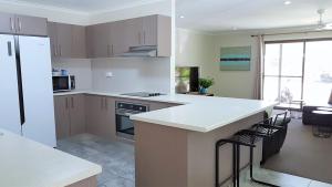 a kitchen with a refrigerator, stove, sink, and dishwasher at Noosa North Shore Pty Ltd in Noosa North Shore