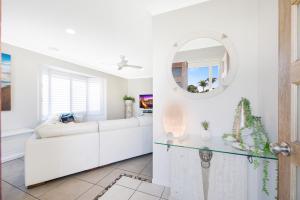 a white living room with a white couch and a mirror at Sweetbrush Place in Mooloolaba