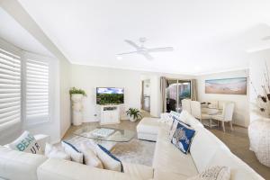 a living room with white furniture and a tv at Sweetbrush Place in Mooloolaba