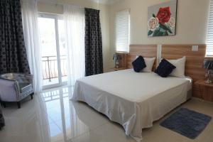 Un dormitorio con una gran cama blanca y una ventana en Self contained apartment with private kitchen Higher Heights, Barbados en Christ Church