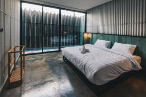 a bedroom with a large bed and a large window at THE TREE Sleep and Space in Trang