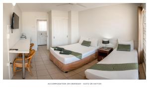 two beds in a room with a desk and a table at Accommodation on Sheridan in Cairns