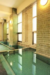 a swimming pool in a large room with windows at K's House Hokkaido - Asahidake Onsen Hostel in Higashikawa
