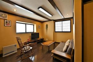a living room with a couch and a desk with a tv at Hida-Takayama Michi in Takayama