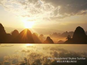 a sunset over the water with mountains in the background at Misty Wonderland ,Yangshuo Xingping in Yangshuo