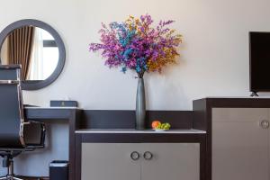 a vase of flowers on a desk with a mirror at Dai Viet Hotel in Thanh Hóa