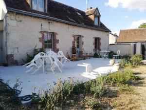 a patio with white chairs in front of a house at Chambre d'hôte Monthodon in Monthodon