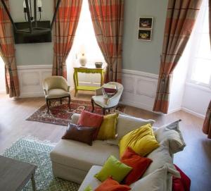 a living room with a couch with colorful pillows at Cottage de la Tour - Duplex troglodyte of 100 m in Azay-le-Rideau +42 photos