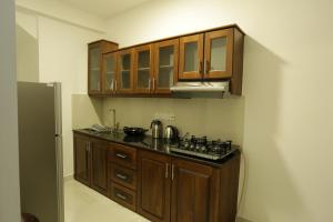 a kitchen with wooden cabinets and a black counter top at Villa Agoura Grand Negombo in Negombo