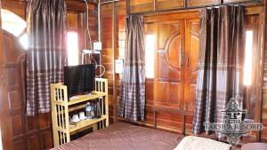 ein Wohnzimmer mit einem TV und Holzwänden in der Unterkunft Taksila Resort ฏักร์ศิลารีสอร์ท in Ban Nong Lup