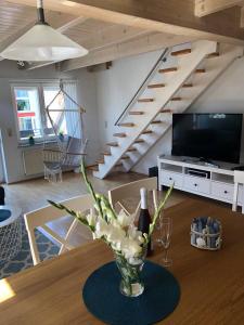 eine Vase mit Blumen auf einem Tisch im Wohnzimmer in der Unterkunft Ferienwohnung Ankerplatz Bodensee in Uhldingen-Mühlhofen