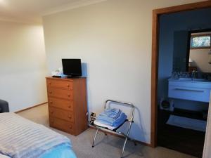 um quarto com uma cama e uma cómoda com um lavatório em Whaka Heights em Christchurch