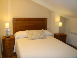 a bedroom with a white bed with two night stands and two lamps at Hostal Los Claveles in Priego