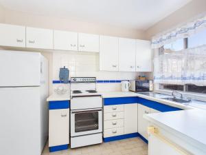 a white kitchen with blue and white appliances at Aquarius 9 in Forster