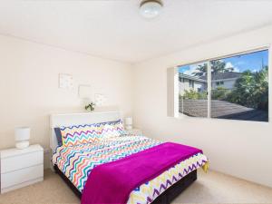 a bedroom with a bed with a purple blanket and a window at Aquarius 9 in Forster