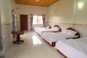 センモノロムにあるMondulkiri Holiday homestayのベッド3台とテーブルが備わる部屋