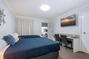 a hotel room with a bed and a television at Raintree Motel Biloela in Biloela