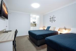 a hotel room with two beds and a television at Raintree Motel Biloela in Biloela