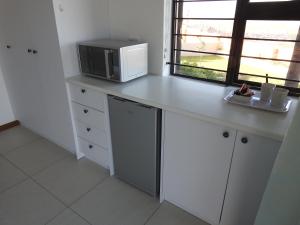 eine Küche mit einer Theke mit einer Mikrowelle und einem Fenster in der Unterkunft Berg en Dal Accommodation in Saldanha