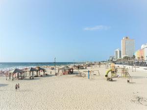 a beach with a playground and people on the beach at Reines5 TLV in Tel Aviv