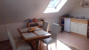 uma cozinha com uma mesa de madeira com cadeiras brancas e uma janela em Haus Wiesengrund em Rauhenebrach